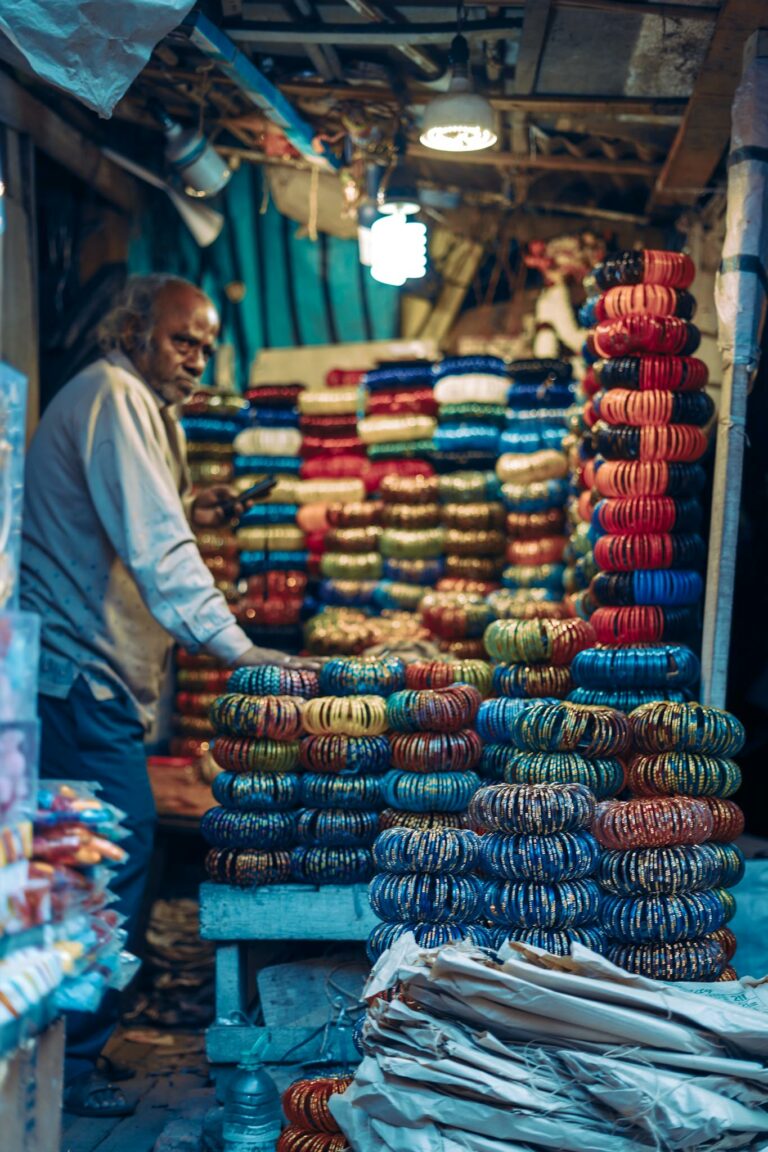 A vibrant bazaar stall displaying a variety of traditional bracelets, man standing behind the counter.